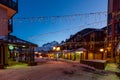 Nightlife in alpine village with traditional wooden houses, shops and restaurants Royalty Free Stock Photo