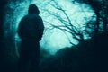 A nightmare horror concept of a man standing in a spooky forest. On a scary, foggy winters day. With a grunge blurred edit