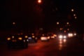 Nights lights of the big city, the blurred night avenue with bokeh traffic lights and headlights of the approaching car Royalty Free Stock Photo