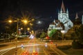 Nightscape cathedral illuminated and car moving light trail long exposure photography in a city landscape