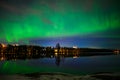 A nightscape view of aurora borealis with a city scape under starry clear sky and reflection from water in ascandenevia Royalty Free Stock Photo