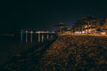 Nighttime beach with umbrellas and city behind.