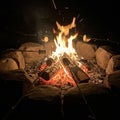 A nighttime campfire is surrounded by a circle of large stones. Flames rise from burn Royalty Free Stock Photo