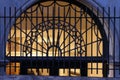 Leaded glass transom window behind an iron fence