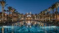 Nighttime luxury at tropical resort pool with dazzling lights and palm trees reflected in water Royalty Free Stock Photo