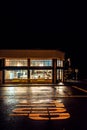 Nighttime shot of hometown storefront with reflections in street.