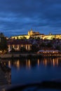 Nighttime photograph taken in Prague, Czech Republic, featuring a view of Prague Castle, the river