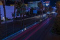 Nighttime scene of Las Vegas cityscape featuring mesmerizing blurred light trails from cars along iconic Strip Road.