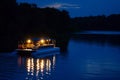 nighttime shot of litup pontoon boat floating on a tranquil lake Royalty Free Stock Photo