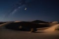 nighttime stars over the dunes of a desert, with crescent moon in view