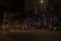 Nighttime view of Collins Avenue with several police cars, their flashing lights illuminating