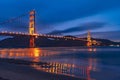 Nighttime view of Golden Gate Bridge reflected in the blurred water surface of San Francisco bay, dark blue sky background; Royalty Free Stock Photo