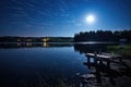 nighttime view of a lake with rods on the dock under bright moonlight Royalty Free Stock Photo