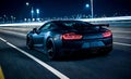 Nighttime view of sports car on city highway, seen from behind, with urban landscape and city lights in background. Dynamic and Royalty Free Stock Photo