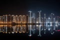 nighttime view of towering high-rises, with the lights shining and reflections shimmering in the water