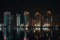 nighttime view of towering high-rises, with the lights shining and reflections shimmering in the water Royalty Free Stock Photo