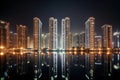 nighttime view of towering high-rises, with the lights shining and reflections shimmering in the water