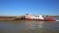 View on HGK pusher boat herkules vessel with cargo barge on river waal against blue sky Royalty Free Stock Photo