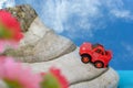 Red toy car driving up a mountain Blue sky with clouds Royalty Free Stock Photo