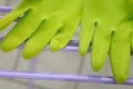 Green household rubber gloves placed on a lilac colored drying rack.