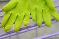 Green household rubber gloves placed on a lilac colored drying rack.