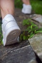 Nike sneakers on the feet of a tourist climbing stones. Close-up. Selective focus, back view