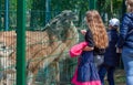 Nikolaev, Ukraine- June 1, 2020: family of mother and her son and daughter walks in the zoo. Girl feeds a llama guanaco through a