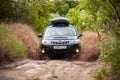 Black Subaru Forester moving at dirty forest road making a lot of water splashes