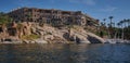 Nile river in Aswan, Egypt afternoon shot showing feluccas and boats in the river with Sofitel Legend Old Cataract Aswan Hotel