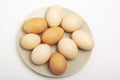 Nine brown raw eggs lie on a gray plate on a white background