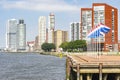 Nine flagpoles with the Dutch flag on the head of the peninsula of Katendrecht with in the background the towers of Montevideo and