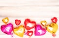 nine shiny pink red and golden heart-shaped balloons with ribbons on a beige and white wooden background. Valentine&#s