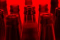 Nine green and one brown bottles shot with red light. Royalty Free Stock Photo