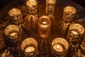 Nine lighted decorative candles, 8 small metal candlesticks surrounding a glass candlestick in the middle of a round metal table