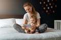 Nine-month-old baby girl sits with her mother and looks on smartphone cartoons. Child is talking to her grandmother via video link Royalty Free Stock Photo