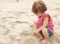 Nine month old baby girl sitting on the beach in beautiful summer day. Little pretty cute european infant child with Royalty Free Stock Photo