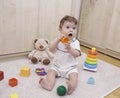 Nine months old baby sitting on the floor and playing with toys at home interior Royalty Free Stock Photo