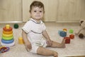Nine months old baby sitting on the floor and playing with toys at home interior Royalty Free Stock Photo