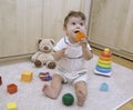 Nine months old baby sitting on the floor and playing with toys at home interior Royalty Free Stock Photo