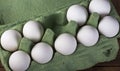 Nine white chicken eggs in a green container on a brown wooden table, top view Royalty Free Stock Photo