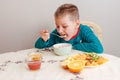 nine-year-old boy in his pajamas sits at a table eating oatmeal with fruit. Healthy baby breakfast Royalty Free Stock Photo