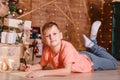 Nine-year-old boy lies on his stomach and writes on the foliage of the paper his wishes for Christmas