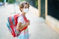 Nine years old girl goes back to school wearing a mask and a schoolbag. Royalty Free Stock Photo