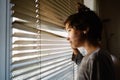 Nine-years-old girl looking out the window through the blinds Royalty Free Stock Photo