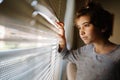 Nine-years-old girl looking out the window through the blinds Royalty Free Stock Photo