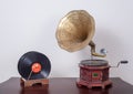 Nineteenth century phonograph gramophone and vinyl records on a wooden table and beige wall