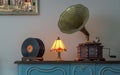 Nineteenth century phonograph and vinyl records on a wooden table and background of beige wall and hanged painting