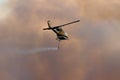 NINGI, AUSTRALIA - NOVEMBER 9 : Waterbomber helicopter with full load heading to fire front into clouds of smoke November 9, 2013