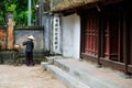 Ninh Binh / Vietnam, 08/11/2017: Local Vietnamese woman with rice hat sweeping the floor of traditional Buddhist temple in the Tam