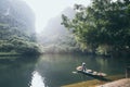 Ninh Binh, Vietnam - May 2019: Vietnamese woman in a wooden rowing boat going through Trang An nature park